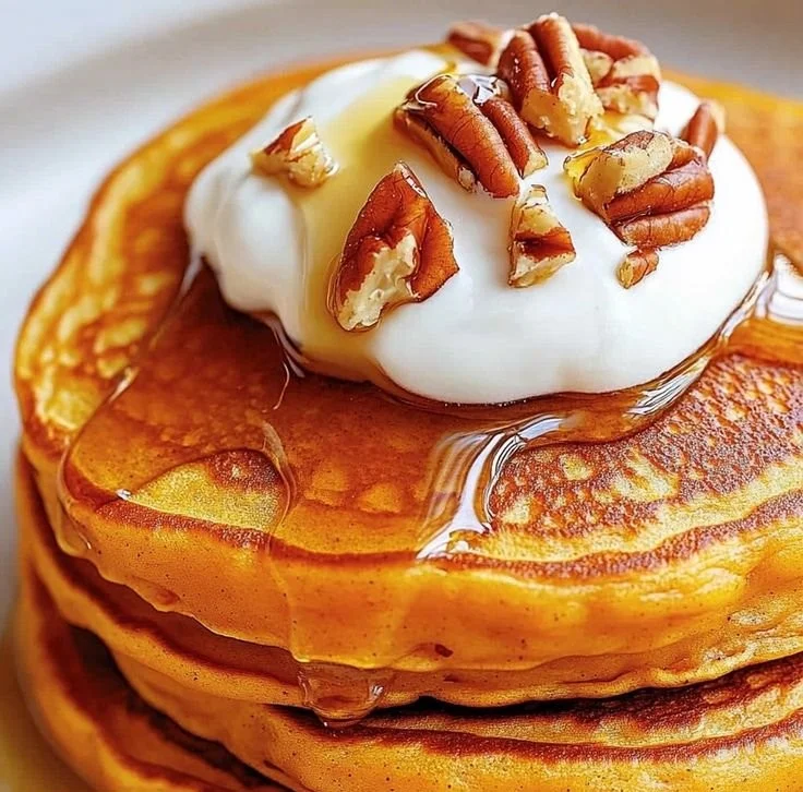 Fluffy sweet potato pancakes stacked on a plate with syrup and fruit