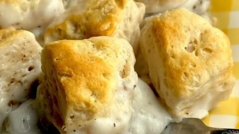 Lazy Biscuits and Gravy Breakfast Casserole on a plate garnished with herbs.